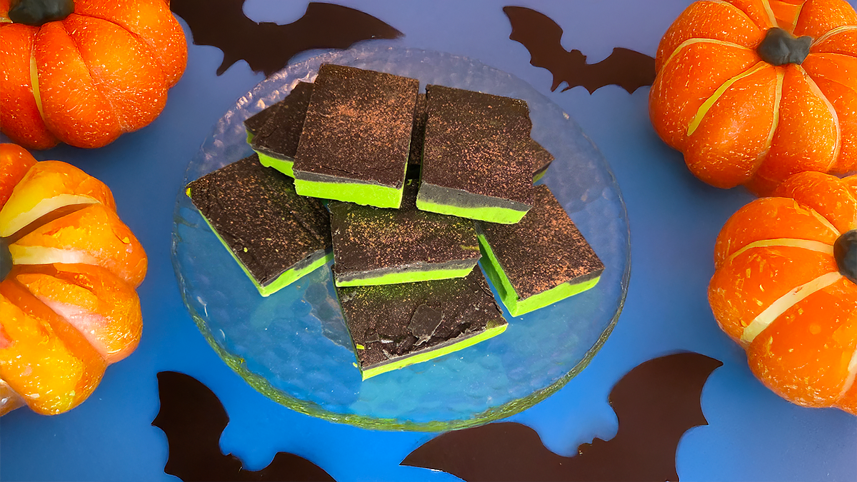 bright green fudge with a caramel layer on top and orange glitter on a halloween themed display